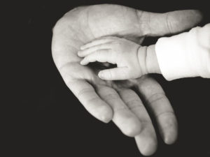 baby hand reaching into palm of older person