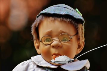 Male preschooler with glasses and a hat sticking out tongue to taste sugar on a spoon